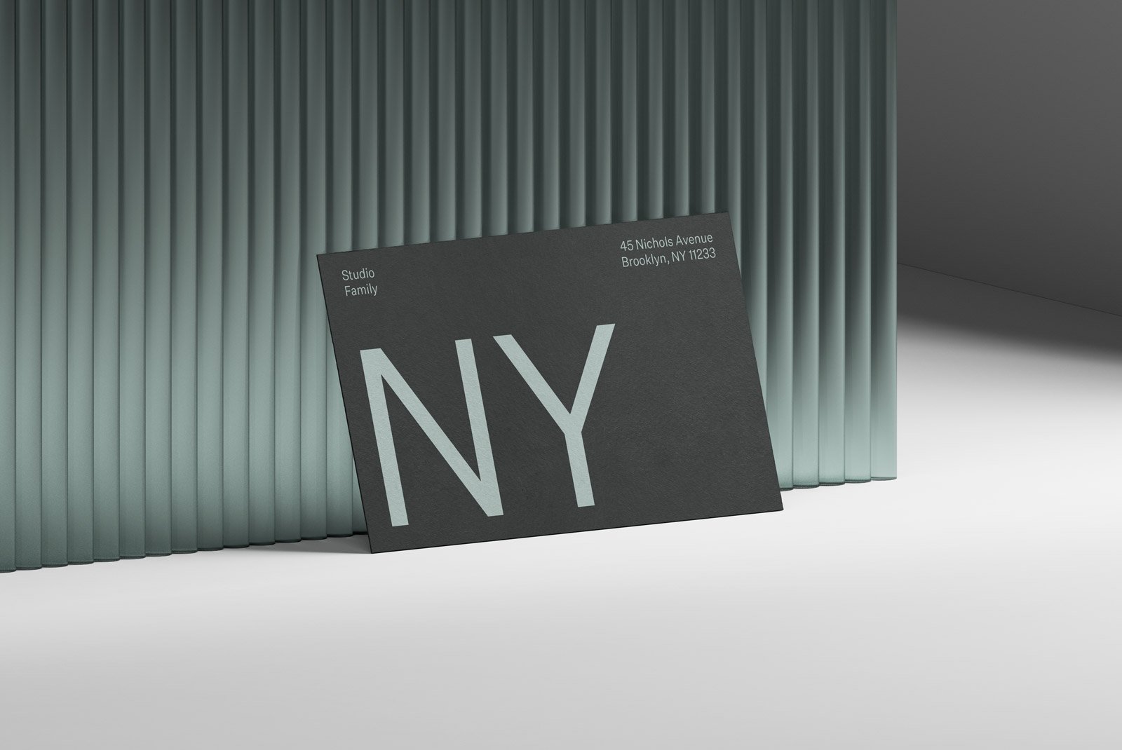 A black business card with large NY text and address details leaning against a modern corrugated backdrop. Perfect for print mockups, graphic design and branding.