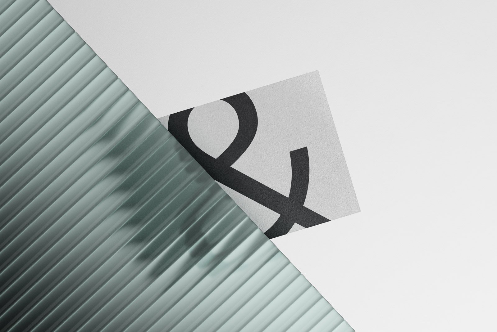 Creative print mockup featuring a textured paper with a bold ampersand design partially hidden behind a translucent corrugated surface ideal for designers.