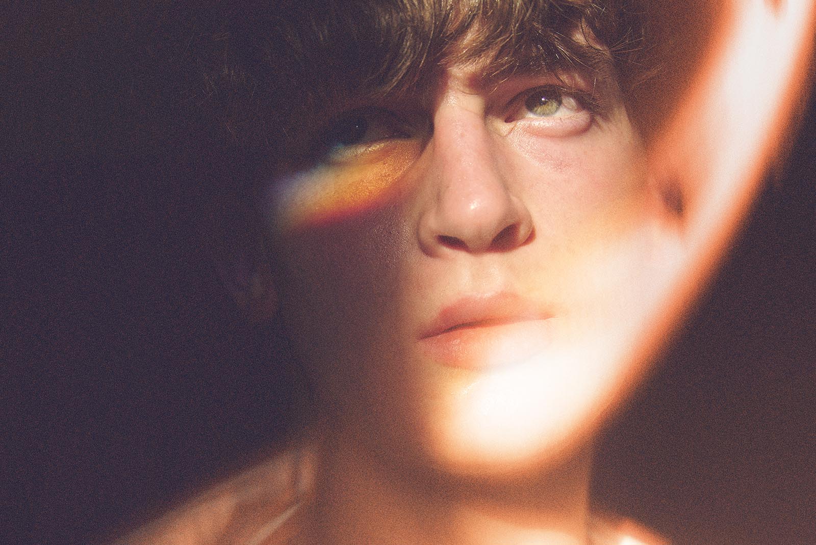 Close-up of a person's face in warm light with a rainbow reflection. Ideal for graphic designers seeking photo effects for digital design assets.
