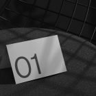 Minimalist print mockup showing a tent card with the number 01 placed on a modern chair. Ideal for graphic designers seeking sleek mockup templates.