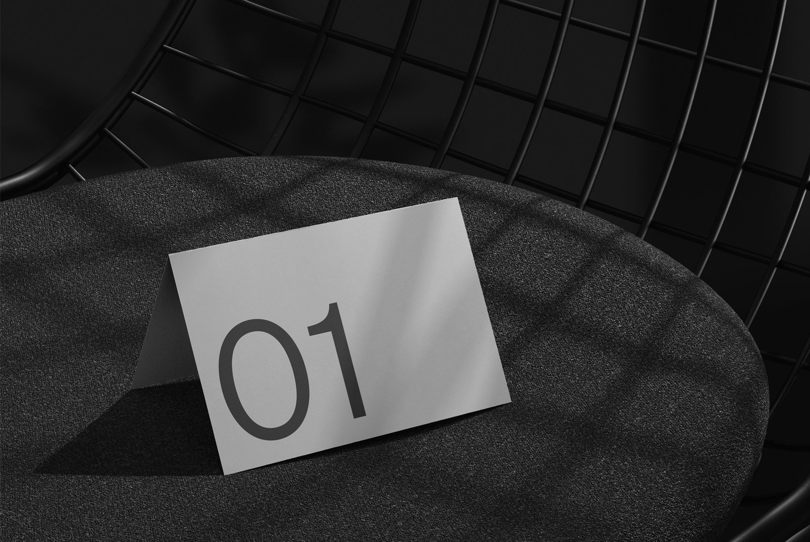 Minimalist print mockup showing a tent card with the number 01 placed on a modern chair. Ideal for graphic designers seeking sleek mockup templates.