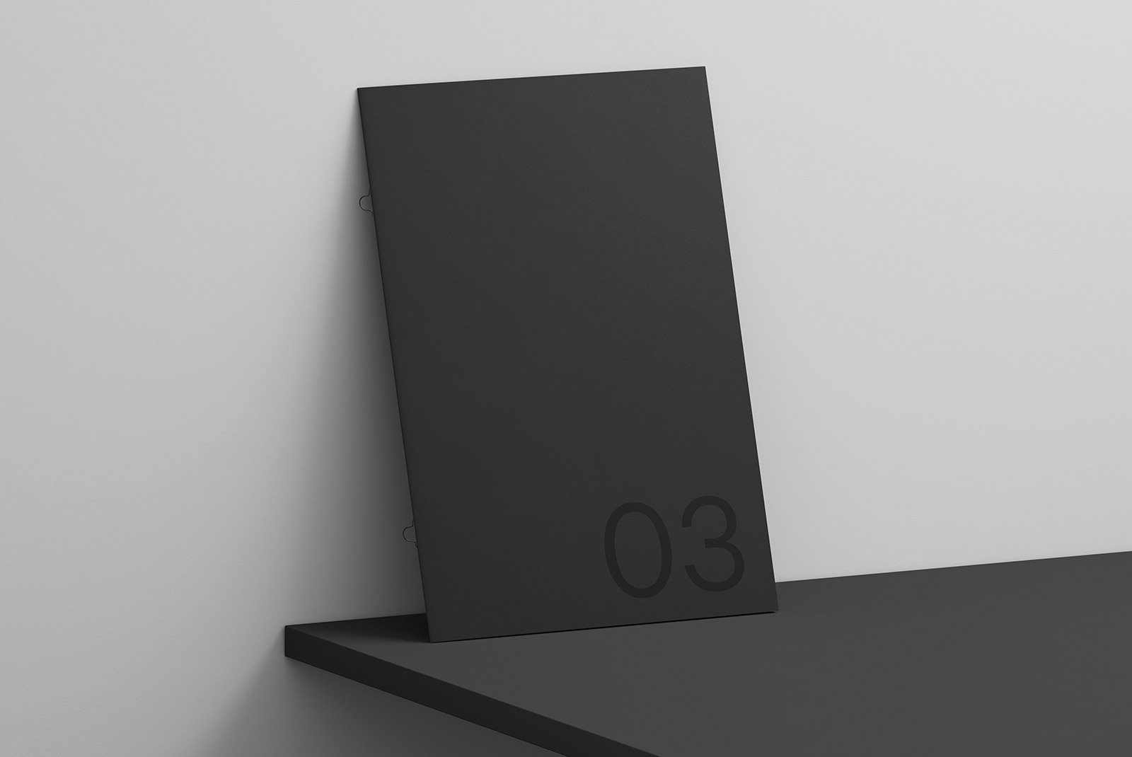 Minimalist black print mockup featuring a booklet with number 03 leaning on a black shelf. Ideal for graphic designers seeking sleek print design templates.