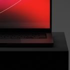 Laptop screen close-up with red gradient background on dark stand. Perfect for tech mockups and digital graphic design presentations.