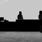 Silhouette of people at a counter in a minimalist gray office setting with a computer monitor. Suitable for tech mockup or branding graphic design projects.