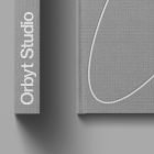 Gray hardcover book mockup with white lettering Orbyt Studio on the spine and minimalist design, perfect for print mockup presentations for graphic designers.