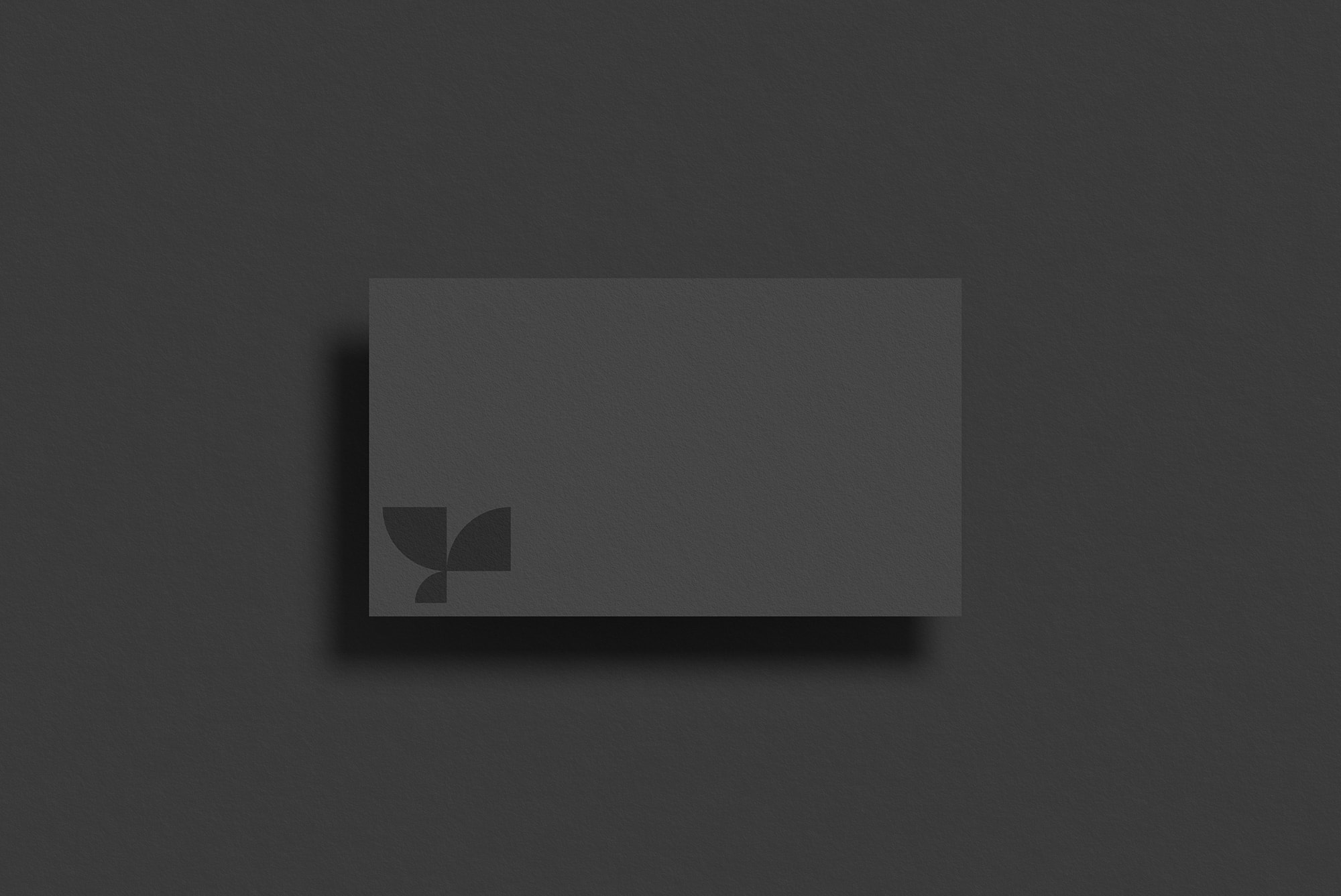 Dark business card print mockup featuring a minimalistic design with a subtle logo in the corner showcasing shadow effects ideal for graphic designers.