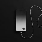 Smartphone with charging cable on black background, ideal for tech mockups, digital devices, minimalist design templates, graphic design resources.