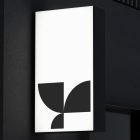 Rectangular illuminated billboard mockup with geometric black shapes on a white background mounted on a dark wall perfect for designers print tech packaging