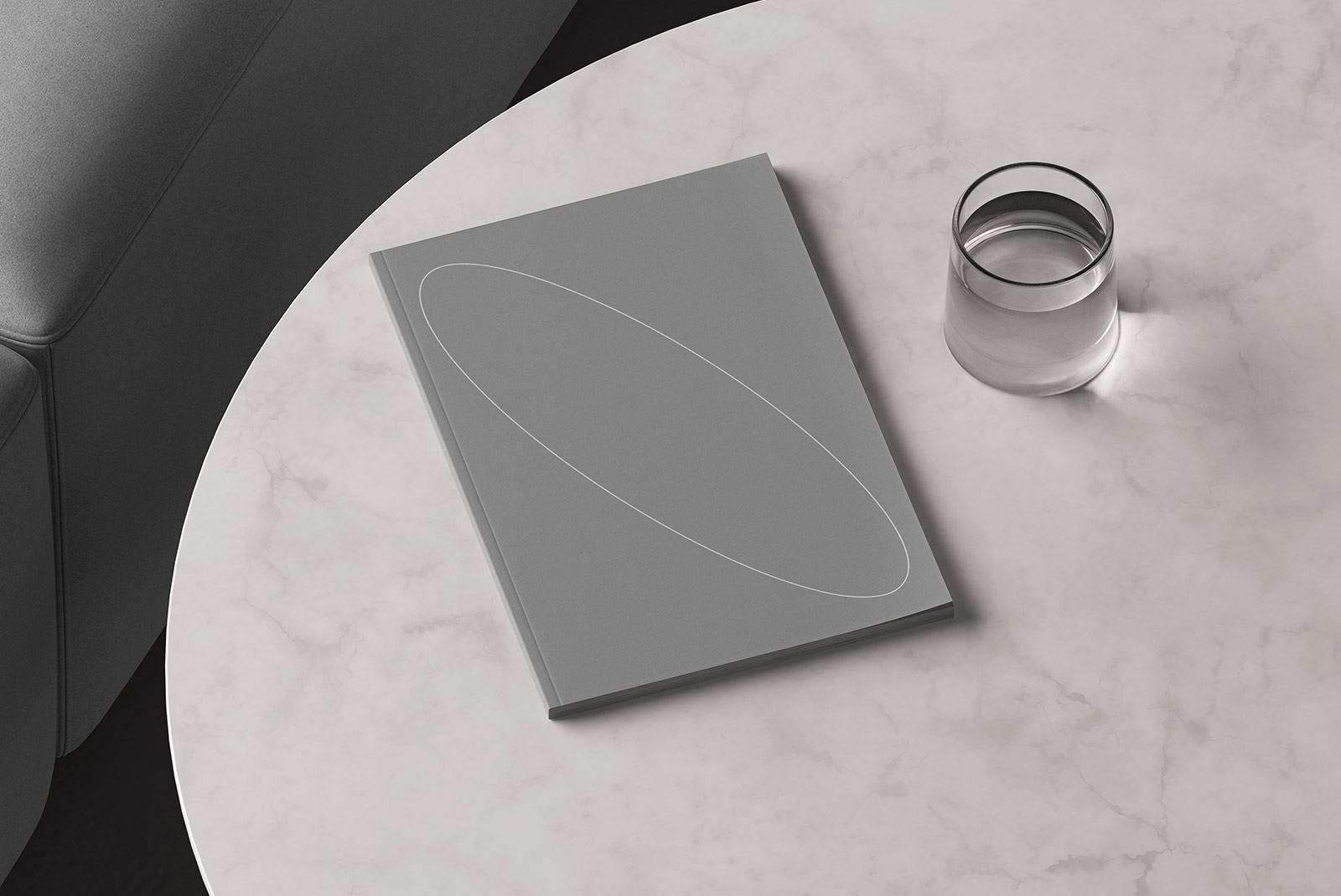 Top view of a gray book mockup and a glass of water on a marble table perfect for print mockups editorial design and graphic designers presenting layouts.