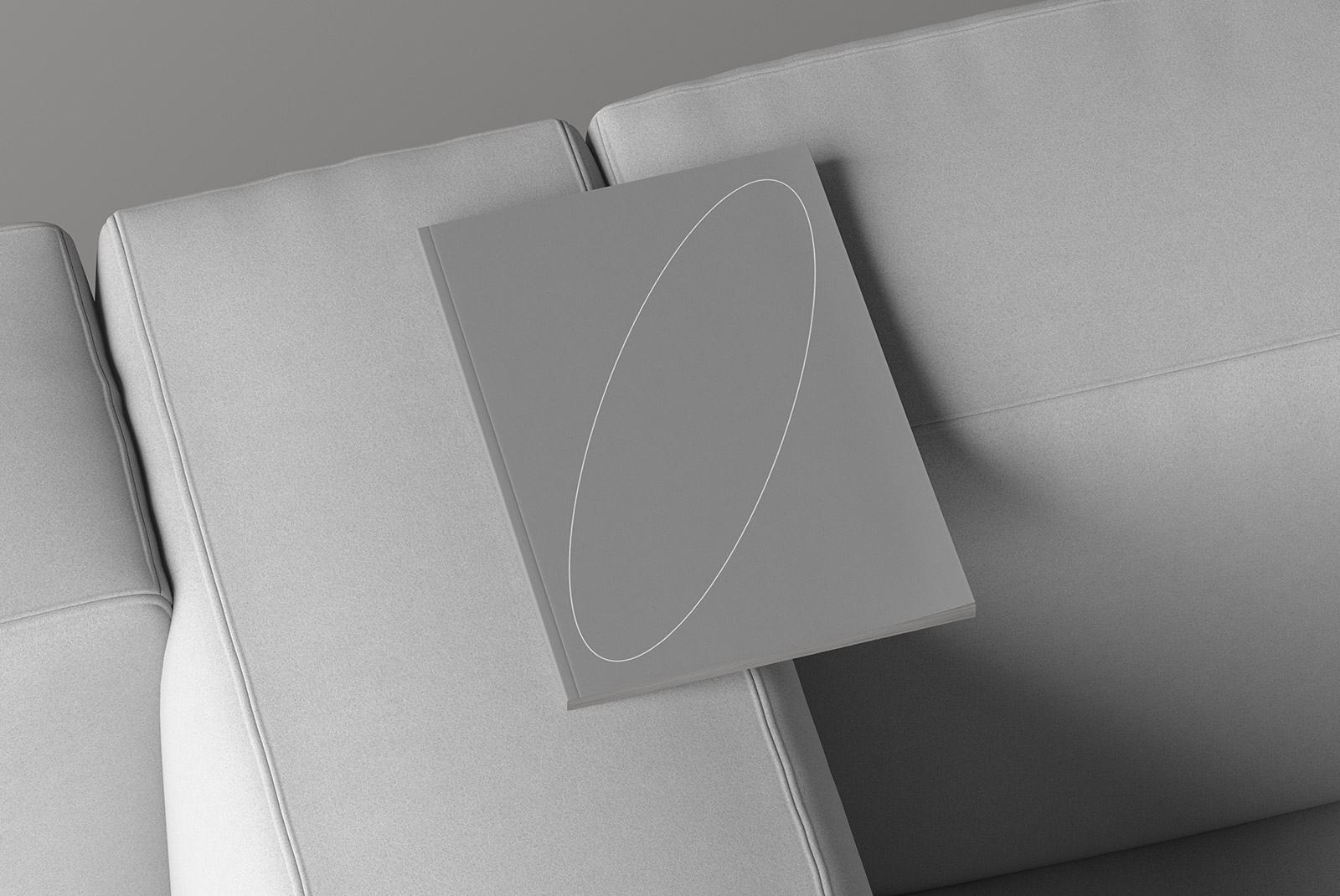 Minimalist book cover mockup laying on a gray couch perfect for print and graphic designers showcasing branding and book cover designs in a realistic setting