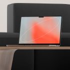 Laptop mockup on wooden table against black couch, ideal for tech mockups and digital presentations. Minimalistic design, perfect for graphic designers and marketers.