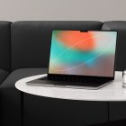 Modern laptop tech mockup on a marble table with a glass of water and a dark sofa background perfect for showcasing digital designs to graphic designers.