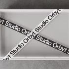 Plastic packaging mockup on a gray concrete floor with black and white Studio Orbyt tape, ideal for graphic designers and packaging design.