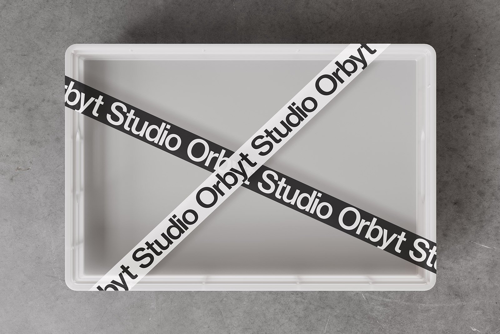 Plastic packaging mockup on a gray concrete floor with black and white Studio Orbyt tape, ideal for graphic designers and packaging design.