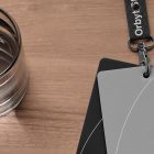Flat lay showing two card mockups attached to a lanyard on a wooden background next to a glass of water suitable for graphic designers.