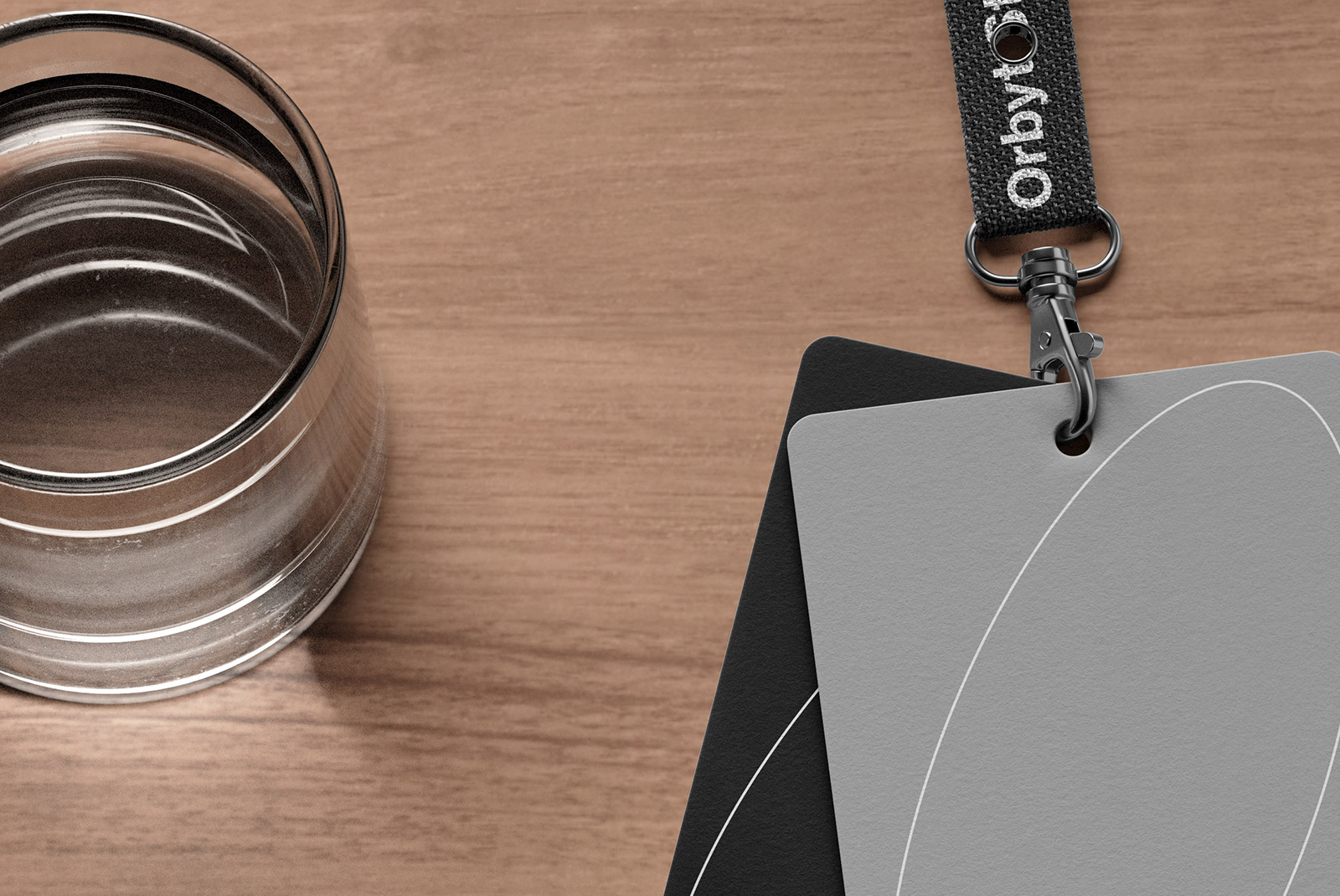 Flat lay showing two card mockups attached to a lanyard on a wooden background next to a glass of water suitable for graphic designers.