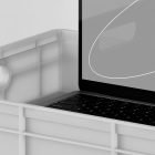 Realistic laptop mockup with a close-up view of a keyboard inside a plastic crate, ideal for showcasing tech designs for graphic designers and mockup enthusiasts.