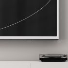 A minimalist tech mockup featuring a sleek black and white monitor on a wall and a turntable on a white cabinet, perfect for graphic designers.